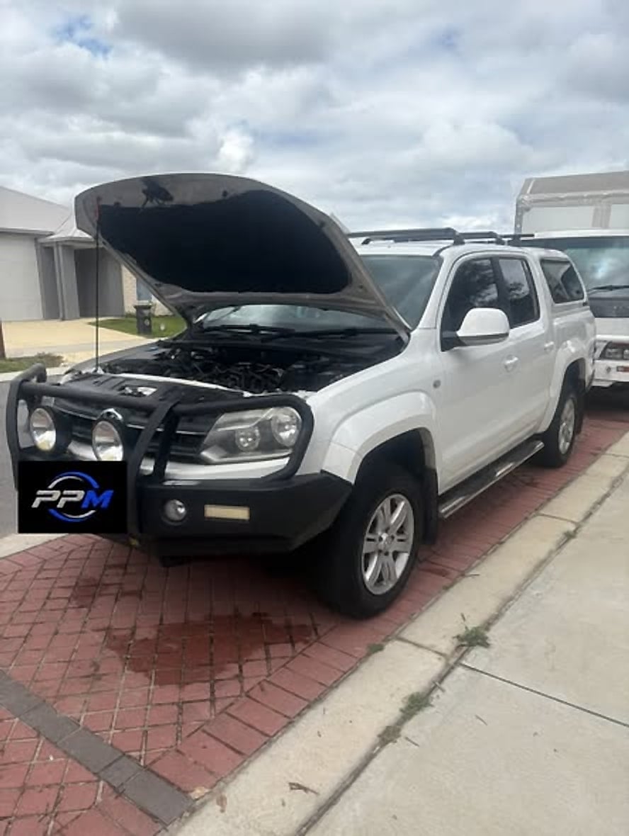 White Volkswagen Amarok with bull bar and the bonnet raised in a driveway