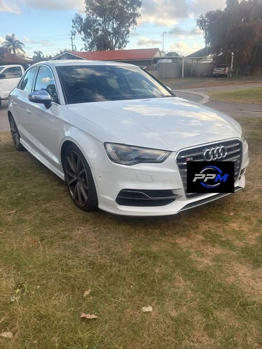 White Audi S3 sedan parked on grass in front of a house
