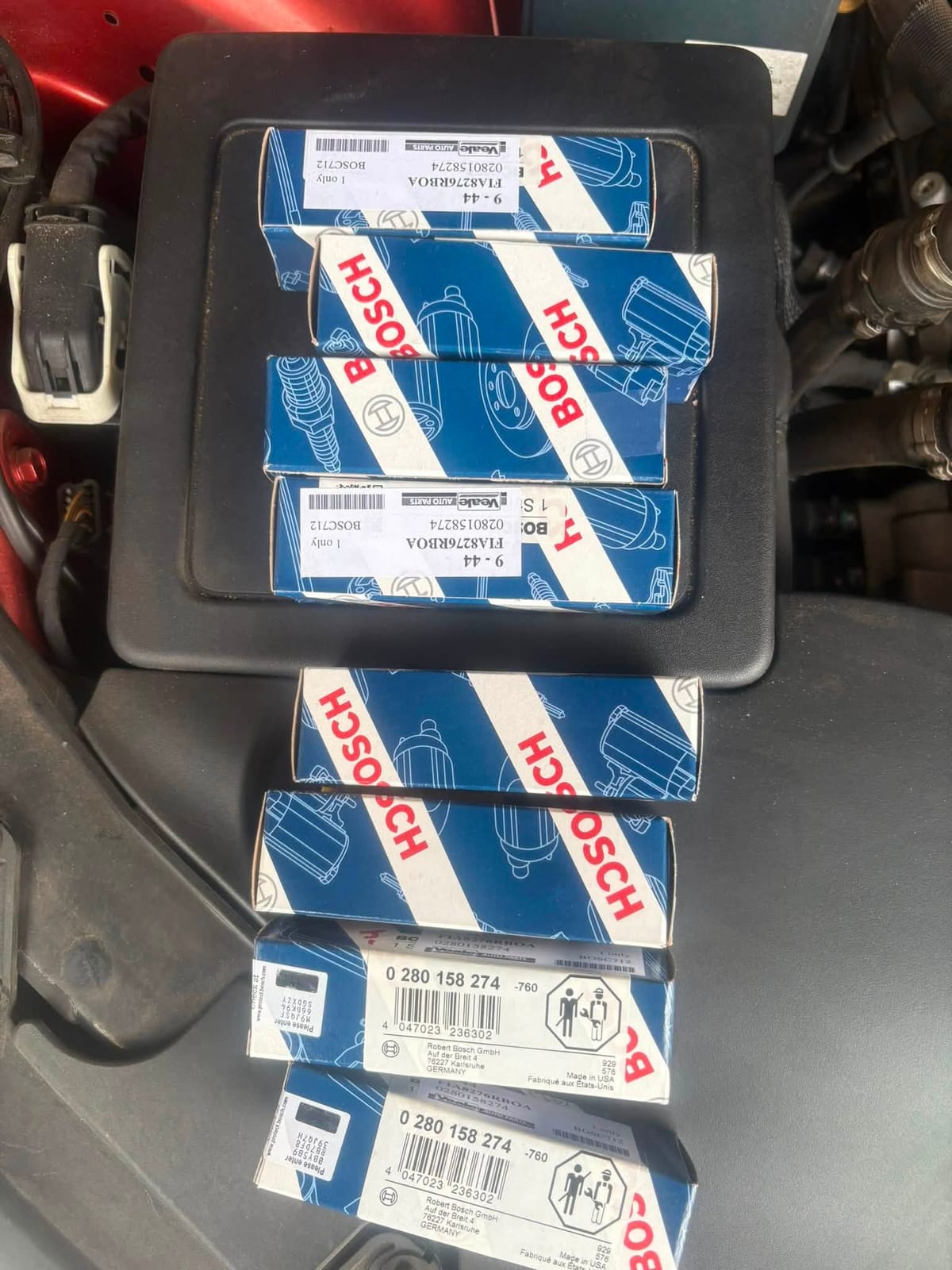Boxes of new Bosch injectors stacked in an engine bay tray