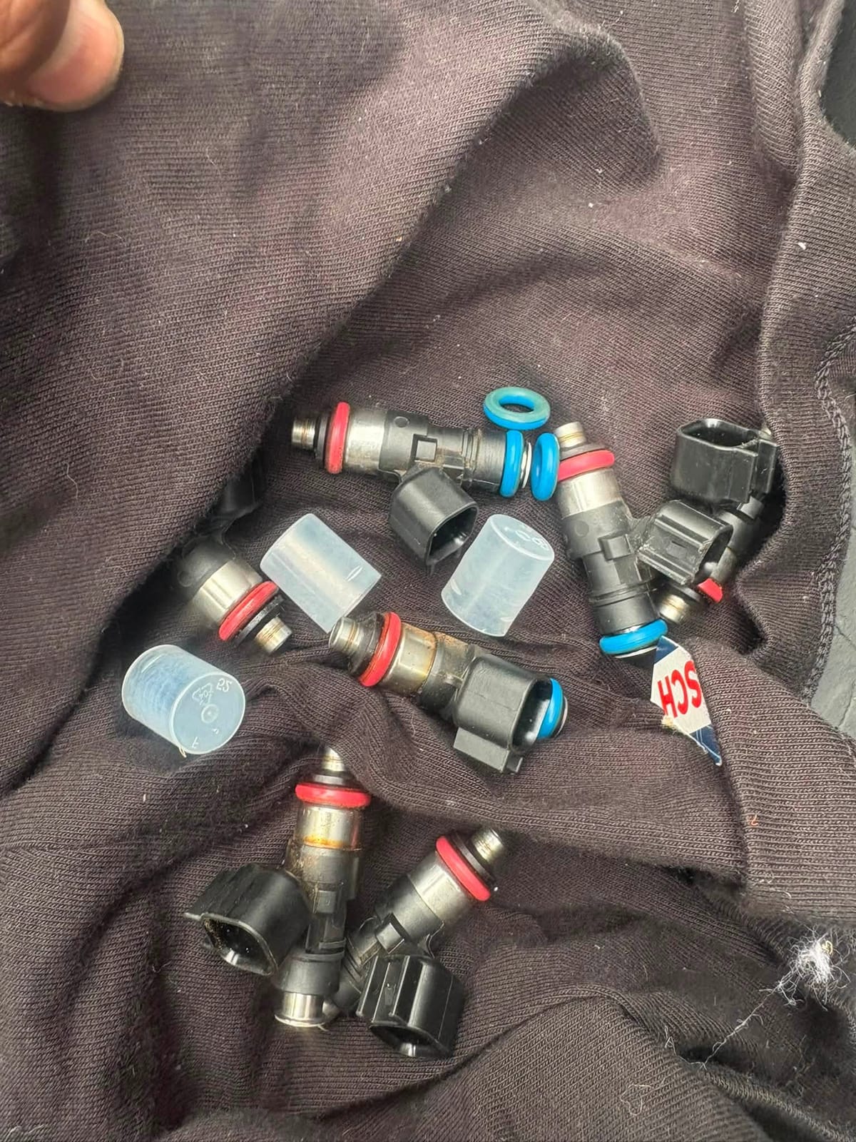 Eight removed fuel injectors laid out on a dark cloth