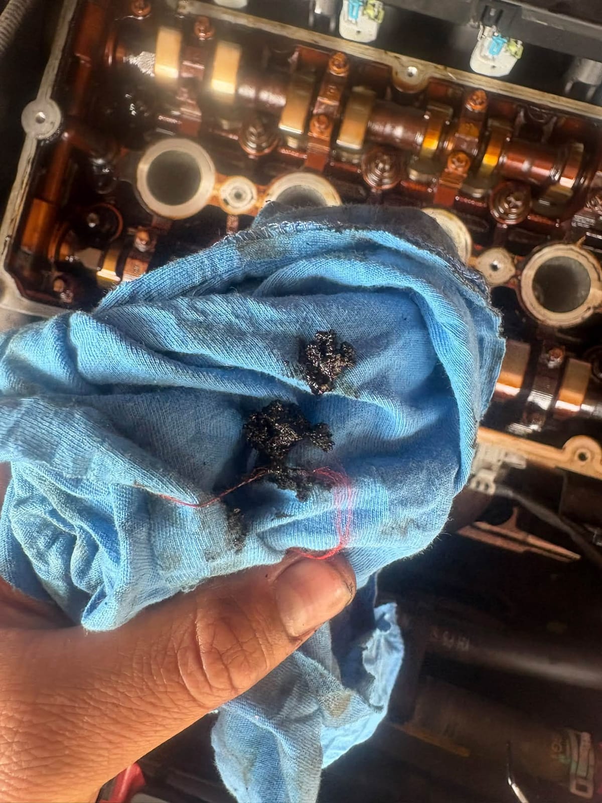 A blue rag holding black oil sludge wiped from the engine