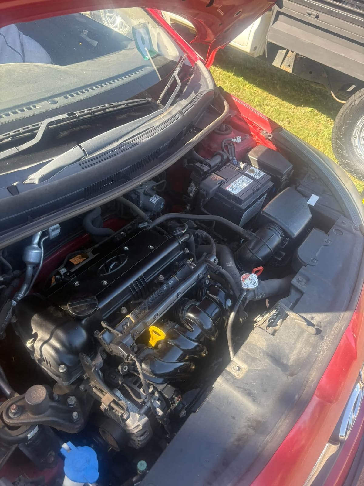 Engine bay of a red Hyundai with the bonnet open, being checked over