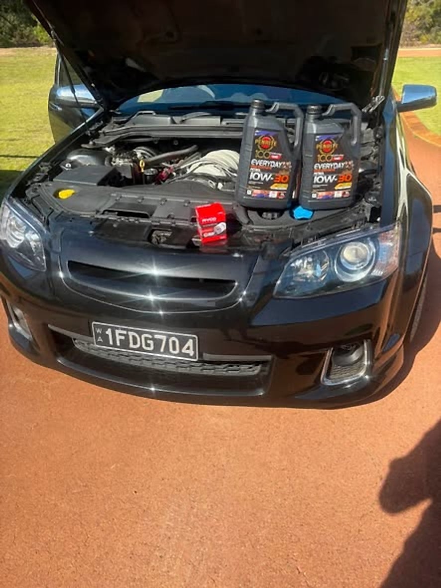Black VE SSV Commodore with the bonnet raised and oil bottles on the engine